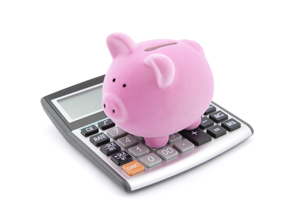 Pink money pig standing on a calculator