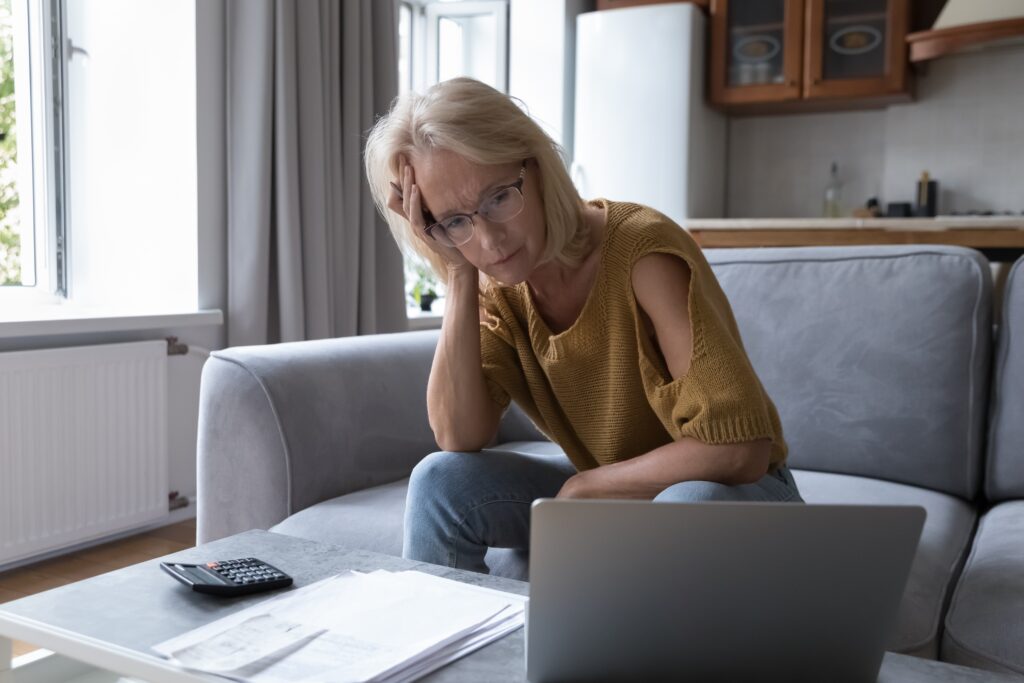 Retired woman looking sad whilst staring at a laptop trying to find her lost pensions